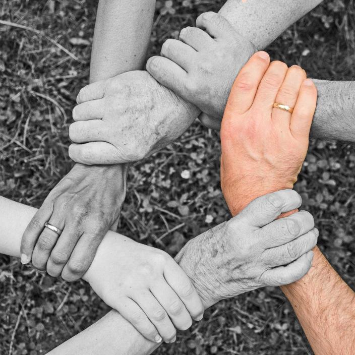 Sechs Hände greifen ineinander, eine Hand farbig, der Rest schwarz-weiß. (c) Anemone123 / Pixabay.com - Lizenz Sechs Hände greifen ineinander, eine Hand farbig, der Rest schwarz-weiß.