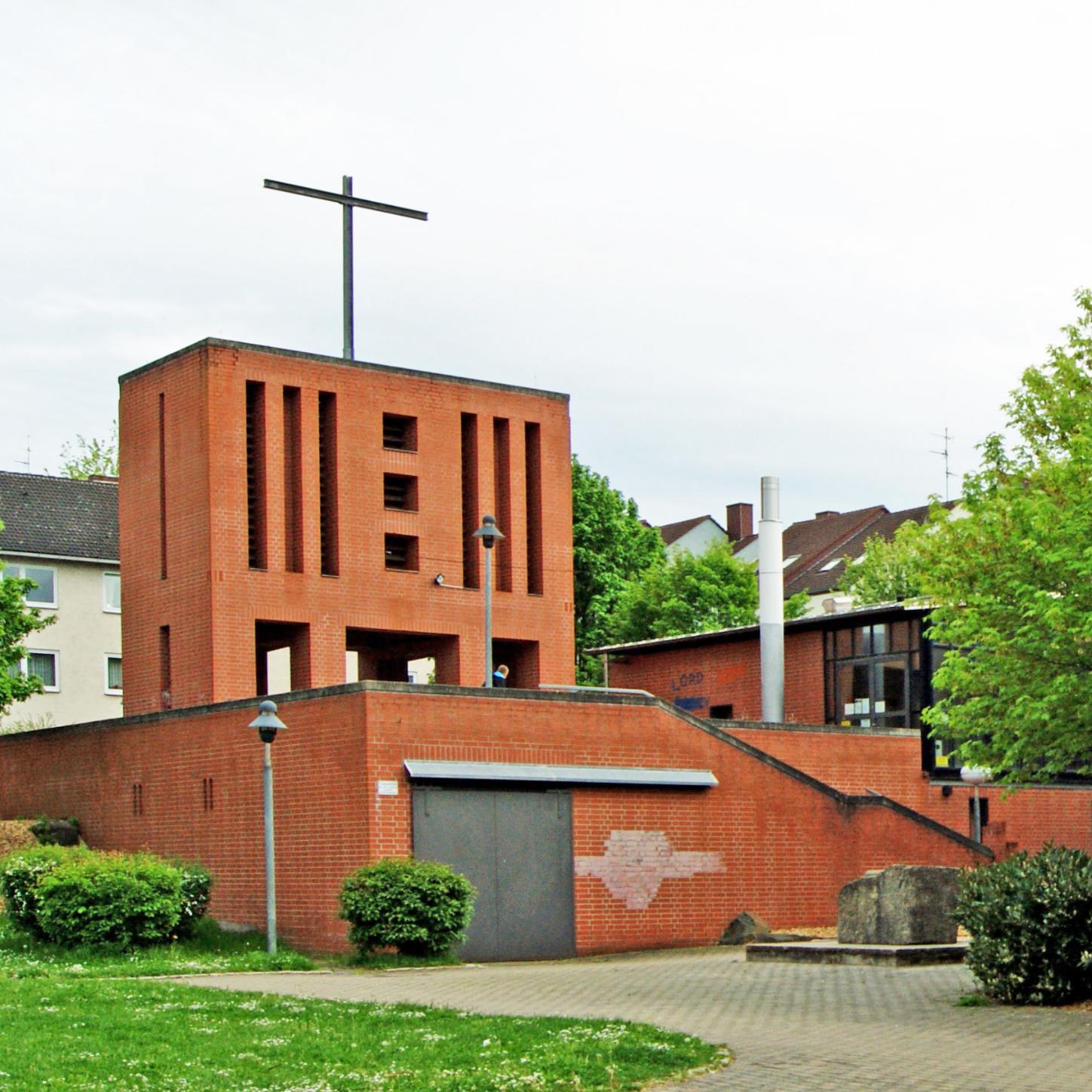 Das Bild zeigt die St.-Franziskus-Kirche mit dem Kirchturm von der Straßenseite her.