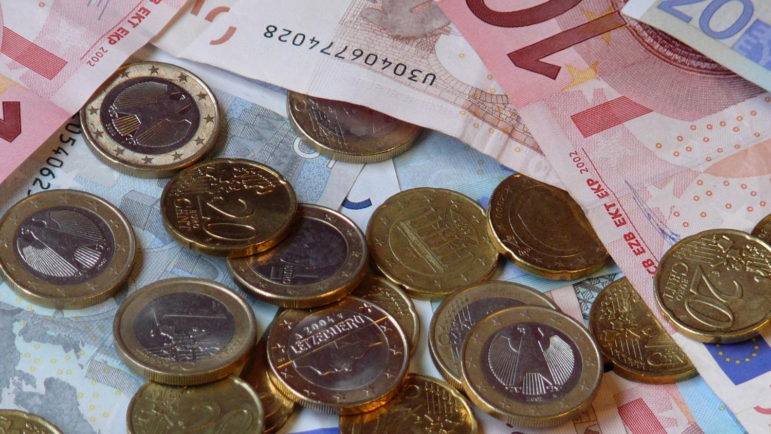Das Bild zeigt Geldscheine und Münzen, die auf einer Unterlage liegen.